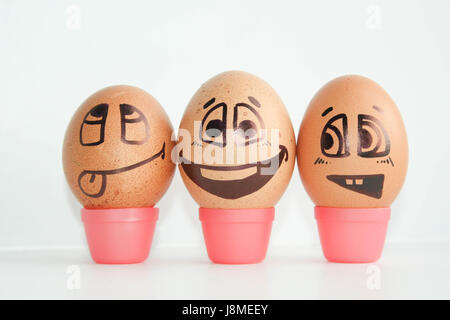 Cheerful eggs three friends, brown eggs. Shows the language and teases. Photo for design. Eggs with painted face. Horizontal orientation of the sheet. Stock Photo