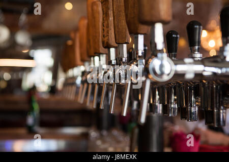 Lot of vintage Golden beer taps in the bar with the bartender in the background Stock Photo