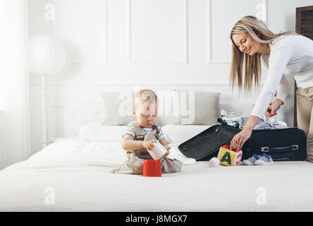 Travelling with kids. Happy mother with her child packing clothes for their holiday Stock Photo