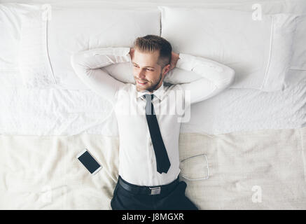 Top view. Young handsome businessman relaxing on bed after a tough day at work Stock Photo