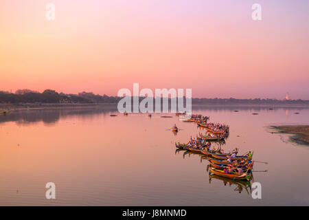 Traditional burmese boats on Taungthaman Lake at sunset, in Amarapura, Mandalay, Myanmar Stock Photo