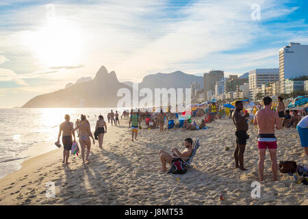 RIO DE JANEIRO - FEBRUARY 6, 2017: Beachgoers on Ipanema Beach sit back to take in the sunset behind Two Brothers Mountain. Stock Photo