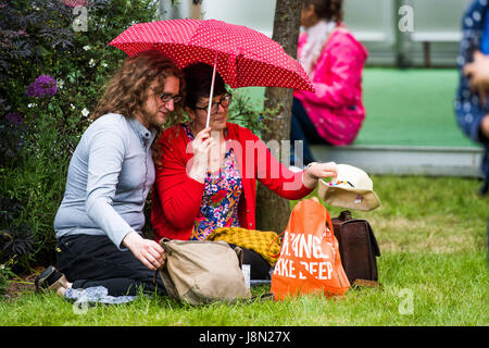 Hay Festival, Wales UK, Monday 29 May 2017 A happy couple share a picnic under theur umbrella in the light rain at the 2017 Hay Literature Festival Now in its 30th year, the festival draws tens of thousand of visitors a day to what was described by former US president Bill Clinton as 'the woodstock of the mind' Photo credit Credit: Keith Morris/Alamy Live News Stock Photo