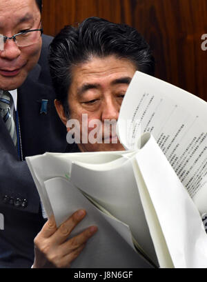 Tokyo, Japan. 30th May, 3017. Japan's Prime Minister Shinzo Abe receives tips of information from his aide while scanning the papers as he attends an Upper House Justice Committee session in the Diet in Tokyo on Tuesday, May 30, 2017. The lower chamber approved a bill allowing authorities to punish those found guilty of planning serious crimes, legislation that opponents say could be used to undermine basic civil liberties, but the proposed legislation, called the 'conspiracy bill,' still requires upper house approval. Credit: Natsuki Sakai/AFLO/Alamy Live News Stock Photo