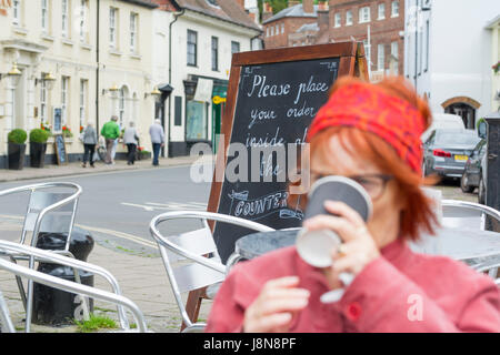 A lady drinking coffee outside at a cafe in the UK. Stock Photo