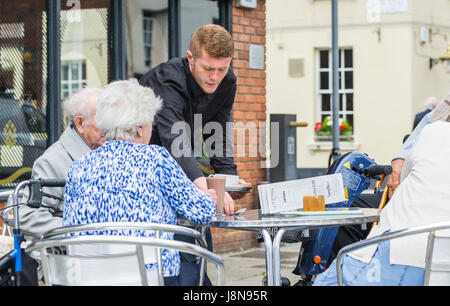 Everyday scene of tourists being served coffee at an outdoor cafe in the UK. Stock Photo
