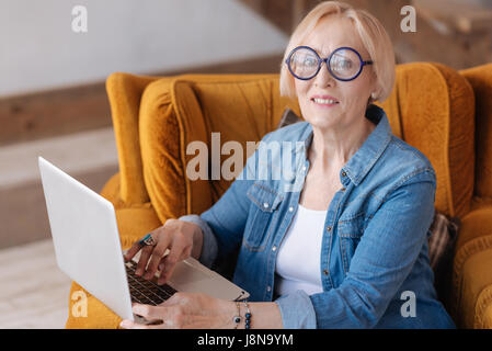 Smile on do. Attractive woman holding hands on computer and keeping smile on face while looking straight at camera Stock Photo