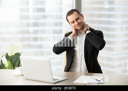 Businessman massaging his tense neck muscles Stock Photo