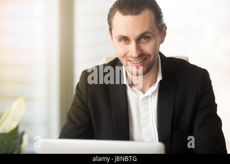 Portrait of successful businessman works on laptop Stock Photo