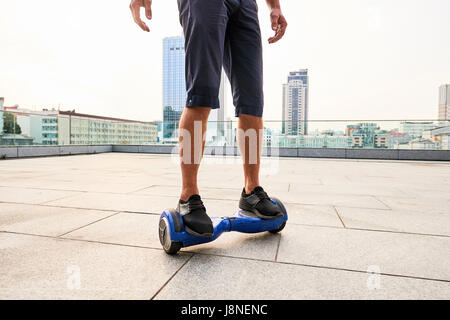 Legs on hoverboard, city background. Stock Photo