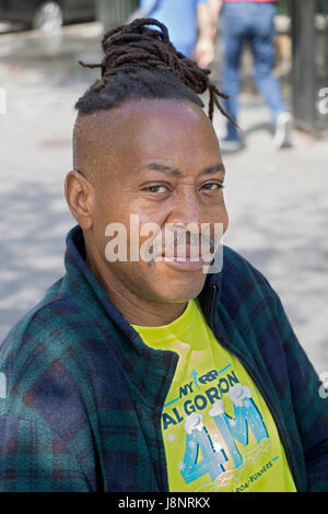 Portrait of a man in Union Square park with a unique hair style that's partially dreadlocks and partially shaven. Manhattan, New York City. Stock Photo