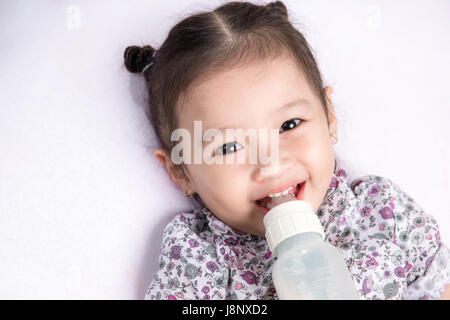 Cute baby girl with a milk bottle on a white blanket Stock Photo