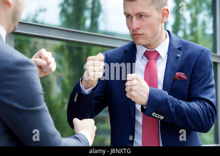 two businessmen standing outside and fighting iwth their fists Stock Photo