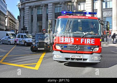 Close up Fire engine emergency services response City of London UK Fire brigade Mercedes Benz appliance 999 call passing London taxi at box junction Stock Photo