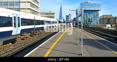 Waterloo East train station platform with public transport electric passenger train and the Shard skyscraper landmark building distant Stock Photo