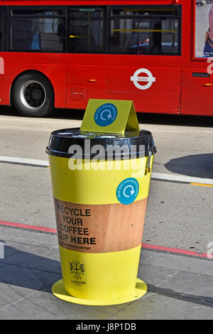 Coffee cup special litter trash bin to recycle paper coffee cups in yellow bins on pavement City of London England UK on trial basis London bus beyond Stock Photo