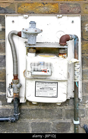 Gas Meter and back of busted cabinet on external outdoor brick wall of business premises completely open to the elements & assumed to be disconnected Stock Photo