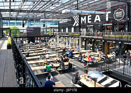 Croydon UK Boxpark covered open space seating area for people to eat food purchased from various vendors trading from adjoining shipping containers Stock Photo