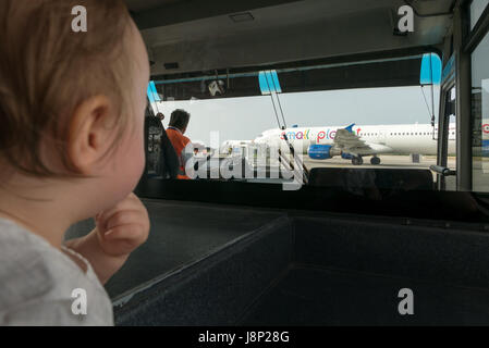 Kos island, Greece - 13 May 2017: Baby look at the plane from bus cabine,  she's very fascinated by the view. Stock Photo