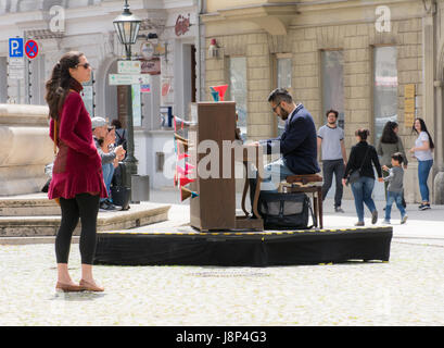 AUGSBURG, GERMANY - MAY 20: Woman listening to an unidentified street musician playing piano in Augsburg, Germany on May 20 ,2017. Foto taken from Max Stock Photo