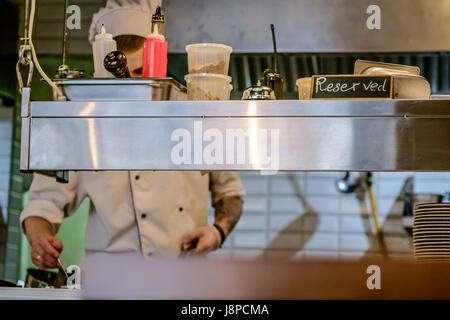 restaurant kitchen close up with Reserved table and  blurred chief cook on the background. Stock Photo