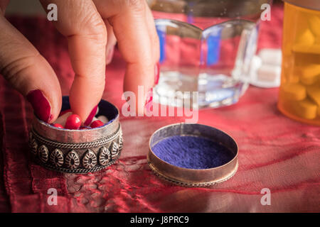 Hand women take capsules red and white in a pillbox metalic old Stock Photo