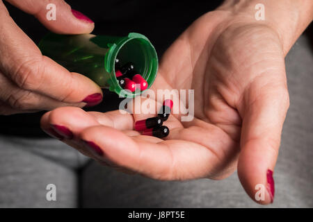Women take capsule red and black with right hand from a bottle amber Stock Photo