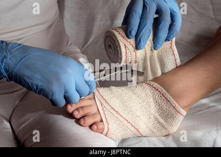 Close-up Of A Nurse Tying Bandage On Patient's Foot Stock Photo