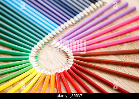Colourful circle of wooden pencils on brown background, wooden table Stock Photo