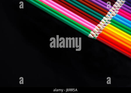 Colored pencils lie opposite isolated on the black background Stock Photo