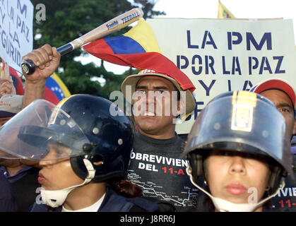 An opposition member waves a bat behind a police line in Caracas December 17, 2002. Thousands of protesters marched to demand the ouster of President 