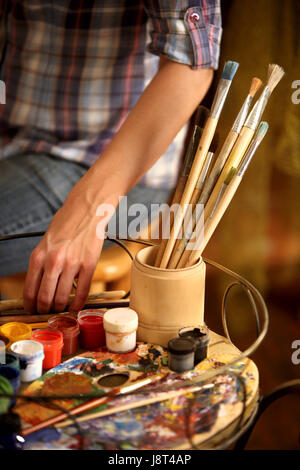 Artist painting easel studio. Cropped shot hands paints with brush. Stock Photo