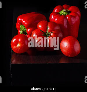 Three big jucy bell peppers and fresh tomatoes on dark wooden background Stock Photo