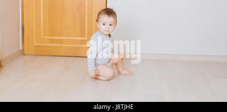 Cute baby boy toddler sitting on the floor in bedroom Stock Photo