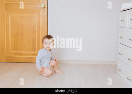 Cute baby boy toddler sitting on the floor in bedroom Stock Photo