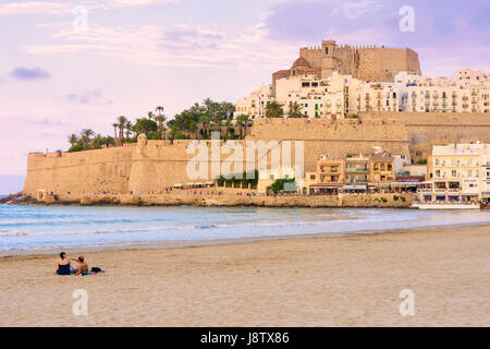 Papa Luna's Castle and old town overlooking a couple on Playa Norte beach at sunset, Peniscola, Spain Stock Photo