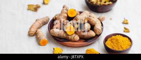 Fresh and dried turmeric roots in a wooden bowl. Stock Photo
