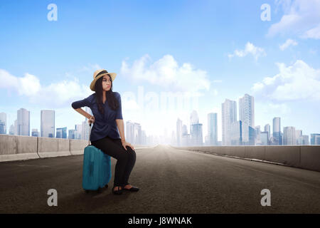 Unhappy beautiful asian traveler woman with luggage waiting transportation on the street Stock Photo