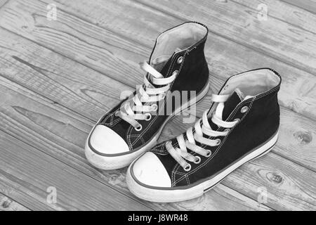 Monochrome black and white grunge wooden background with vintage canvas sneakers Stock Photo