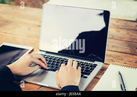 Business man hand using laptop on table in coffee shop with vintage toned filter. Stock Photo