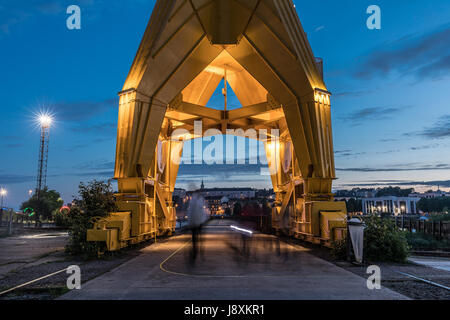 Passage of people under the yellow crane titan by night in long exposure (Nantes, France) Stock Photo