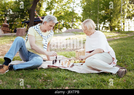 Calm aged couple playing chess at the picnic Stock Photo