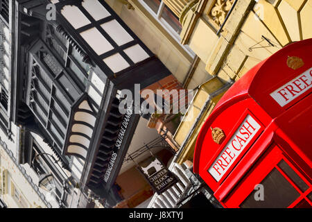 England, Cheshire, Chester, Iconic red telephone box converted to ATM on Eastgate Street with black and white architecture behind. Stock Photo