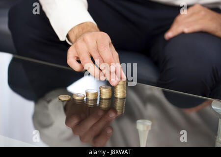 Businessman hand building money column on glass desk Stock Photo