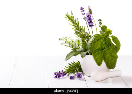 bunch of garden fresh herbs in a mortar over white isolated background Stock Photo