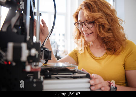 Positive joyful woman checking the work of a 3d printer Stock Photo