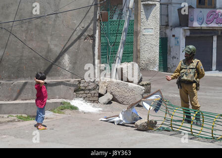 Srinagar, India. 30th May, 2017. An Indian paramilitary personnel plays with a child during curfew in Kashmir. Curfew has been put in plcae in Kashmir on third day to counter the protests against the killing of Kashmiri Rebel Sabzar in an encounter with Indian Forces in Tral area of Kashmir on Saturday. Credit: Muzamil Mattoo/Pacific Press/Alamy Live News Stock Photo