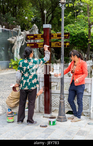 Guilin, China.  Elephant Trunk Hill Park.  Workers Varnishing Direction Signs. Stock Photo