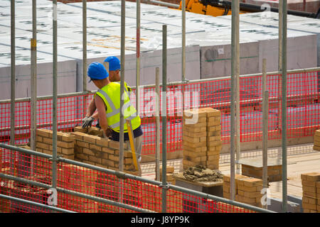 Two bricklayers laying bricks on a new housing development Stock Photo