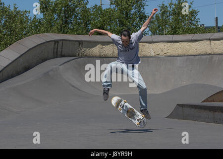 A skateboarder executing a kickflip in the air Stock Photo